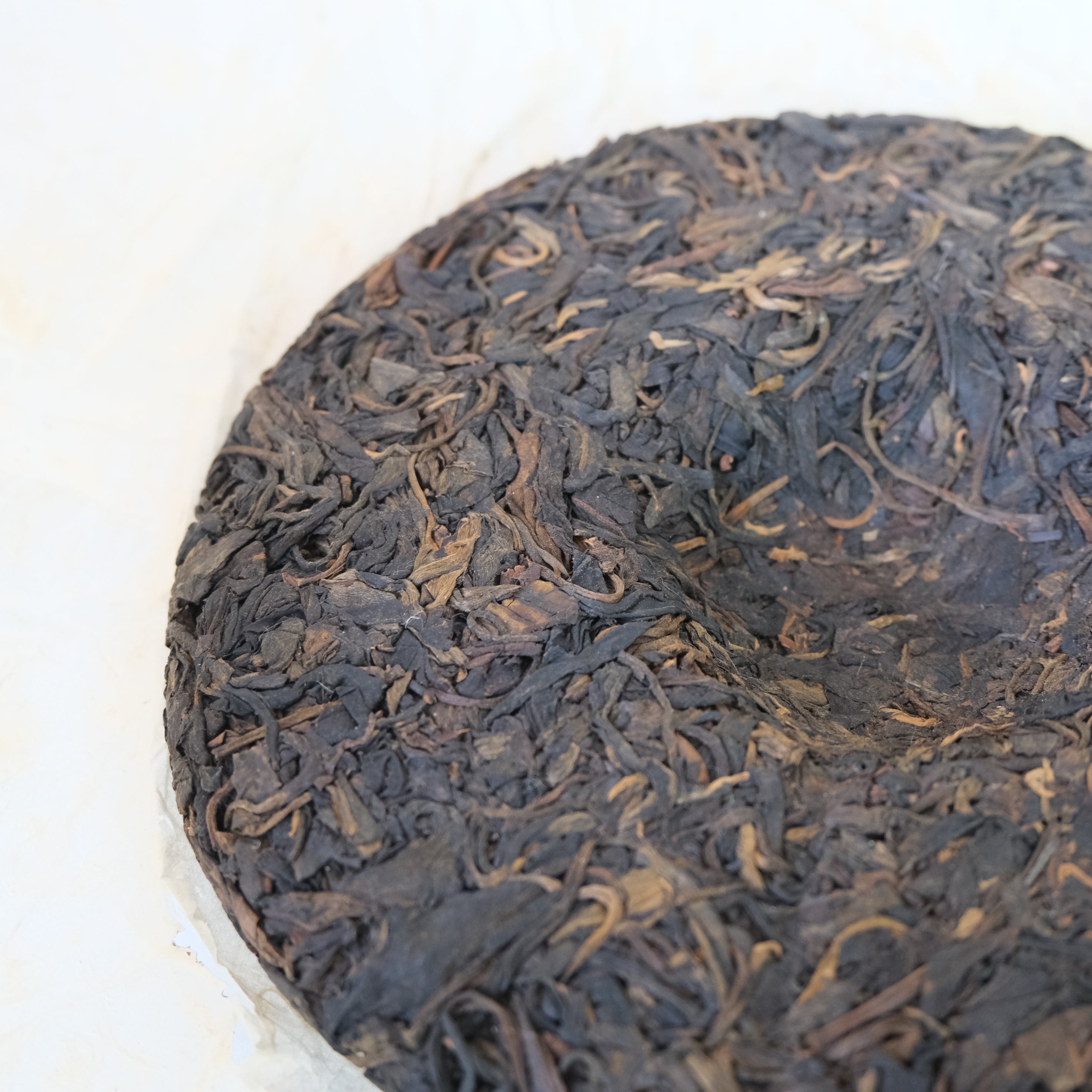 Close-up of a round cake of black tea leaves on a white background