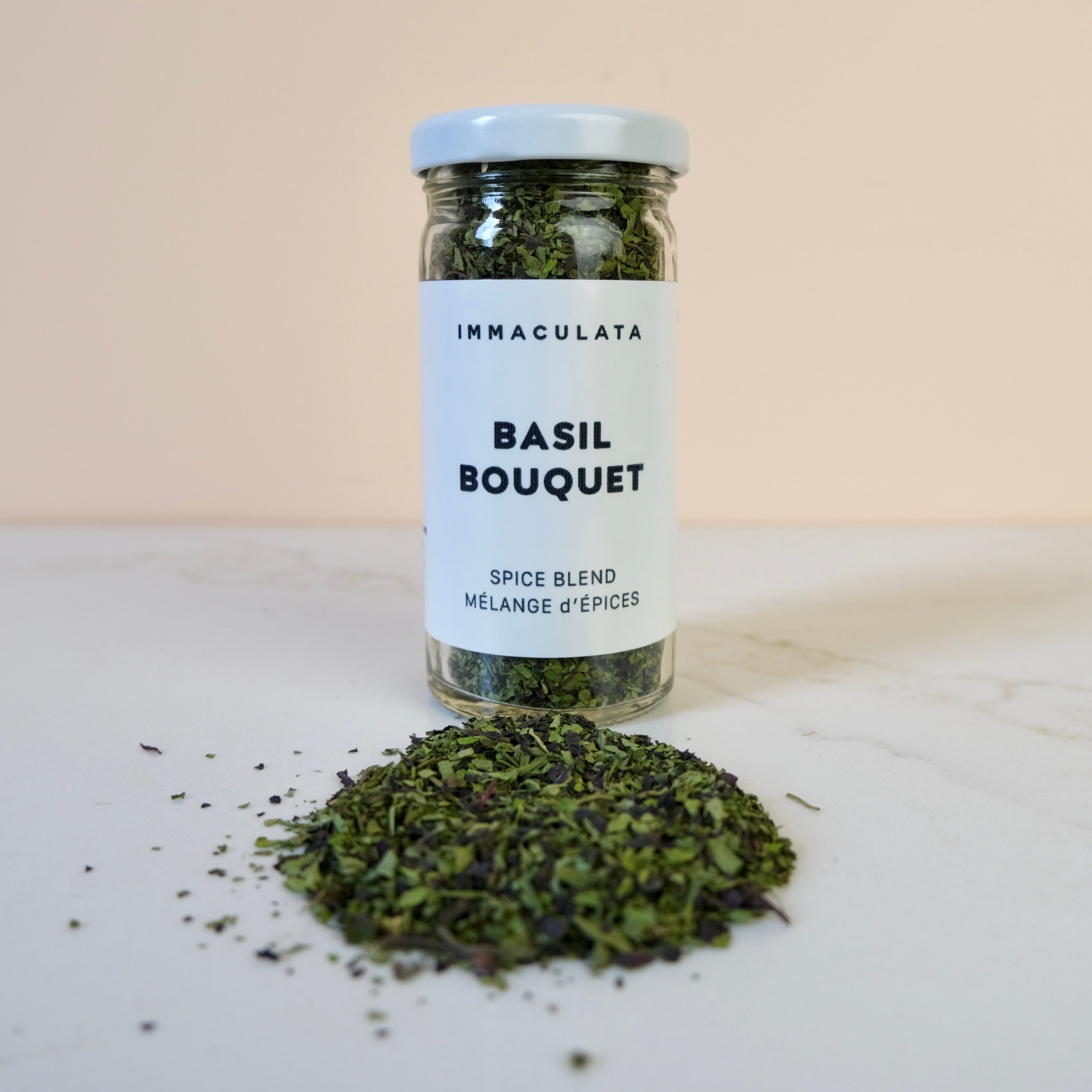 Jar of basil bouquet spice blend with a white label on a light surface.