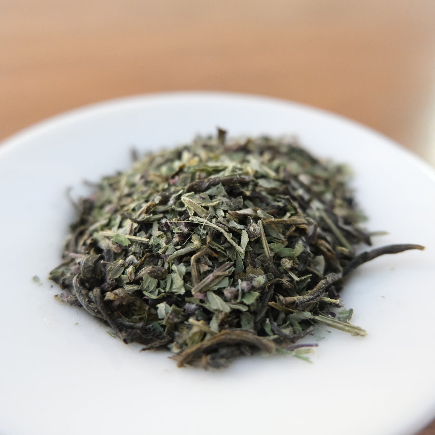 Dry green herbs on a white plate with a blurred background