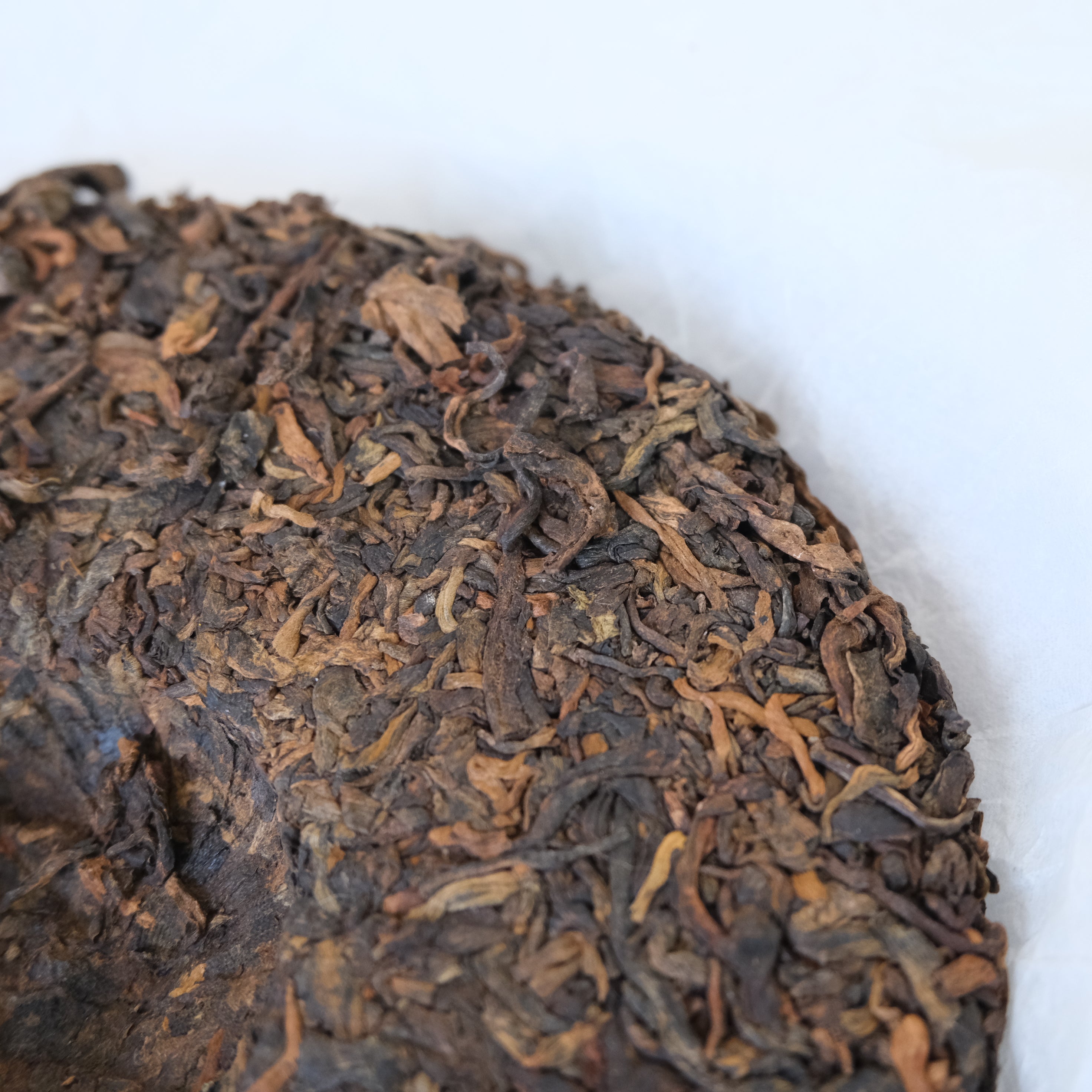 Close-up of a round cake of black tea leaves on a white background