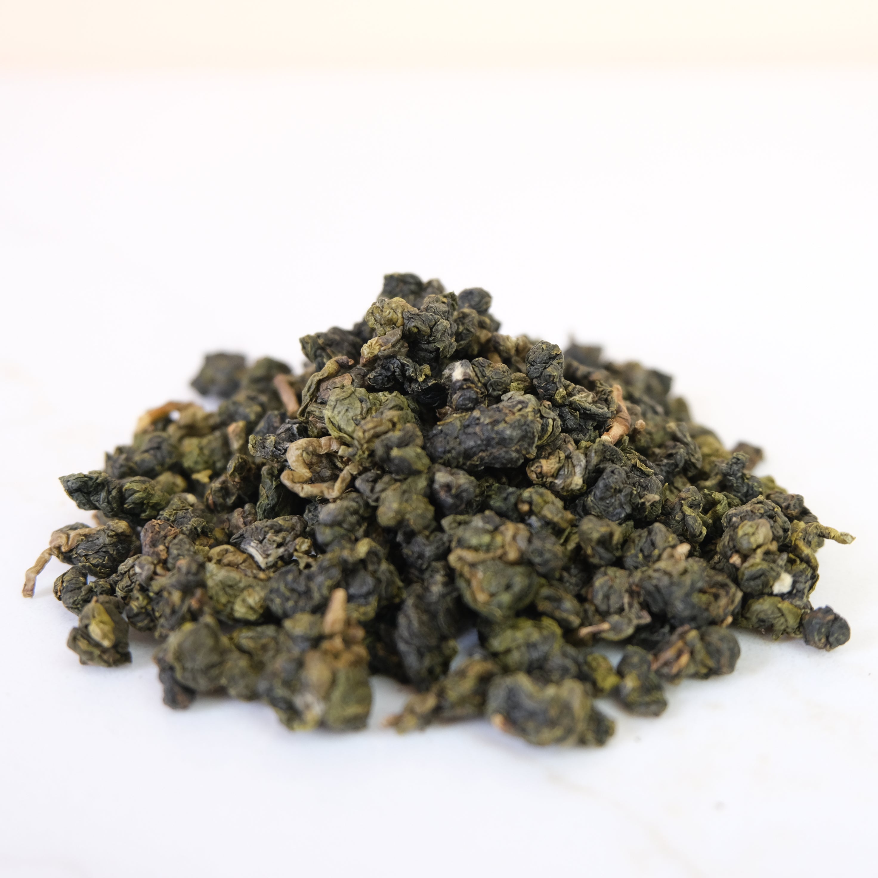Pile of green tea leaves on a white background