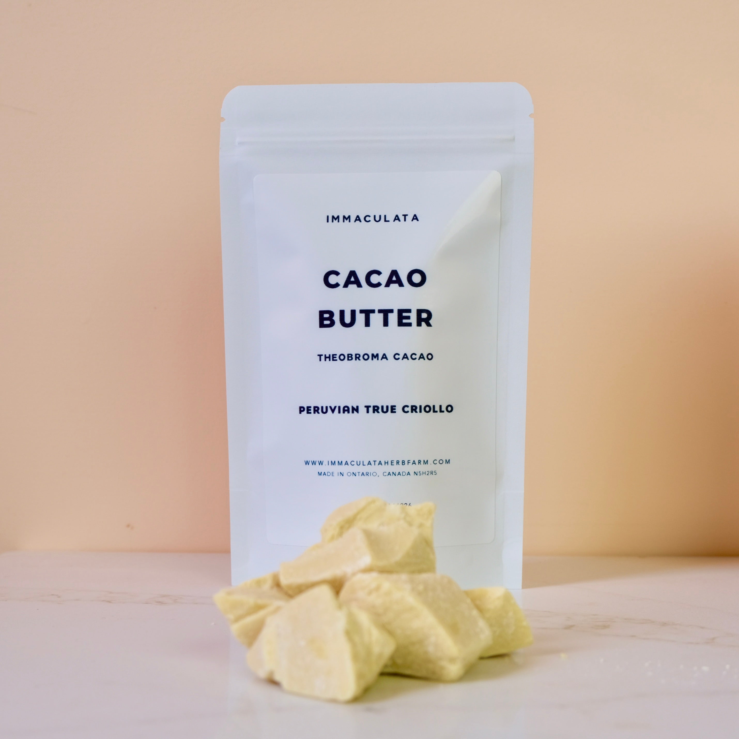 Cacao butter with a white packaging labeled 'Immaculata' on a beige background