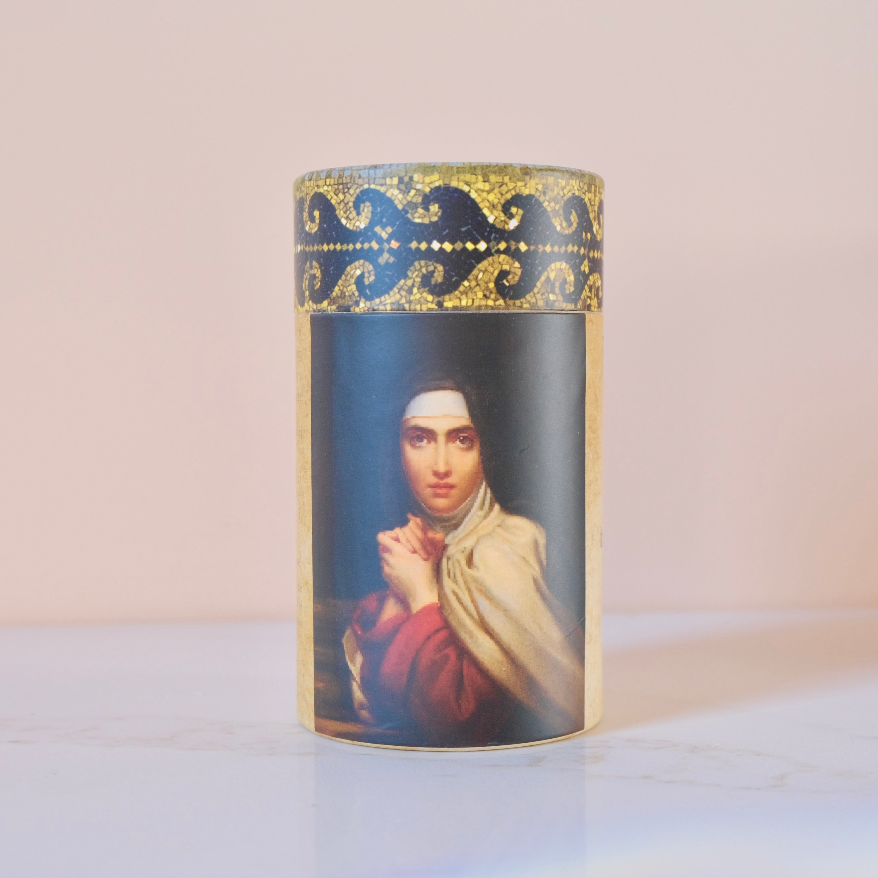 Decorative cylindrical container with a portrait of St Teresa of Avila on a light background