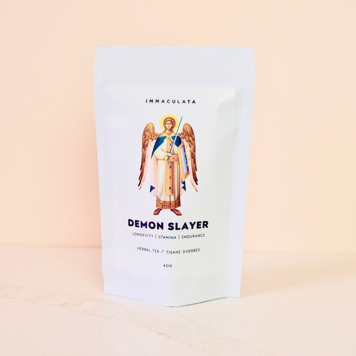 Tea package labeled 'Demon Slayer' by Immaculata Herb Farm with an angel illustration on a beige background