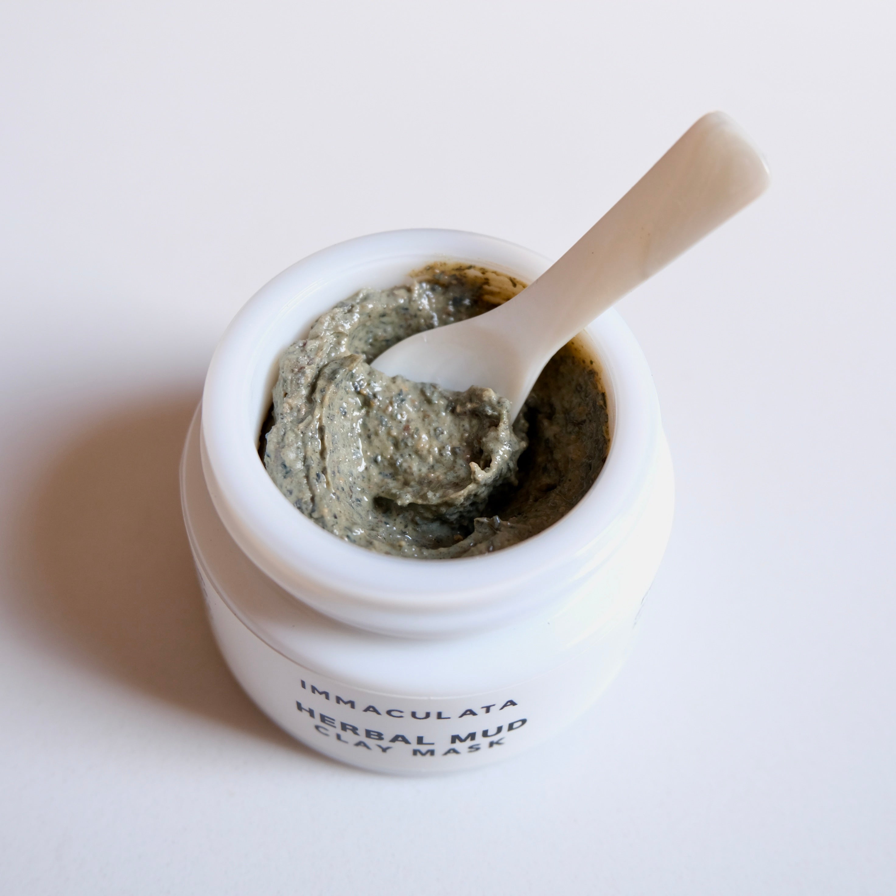 Jar of Immaculata Herbal Mud Clay Mask with a spoon on a white background