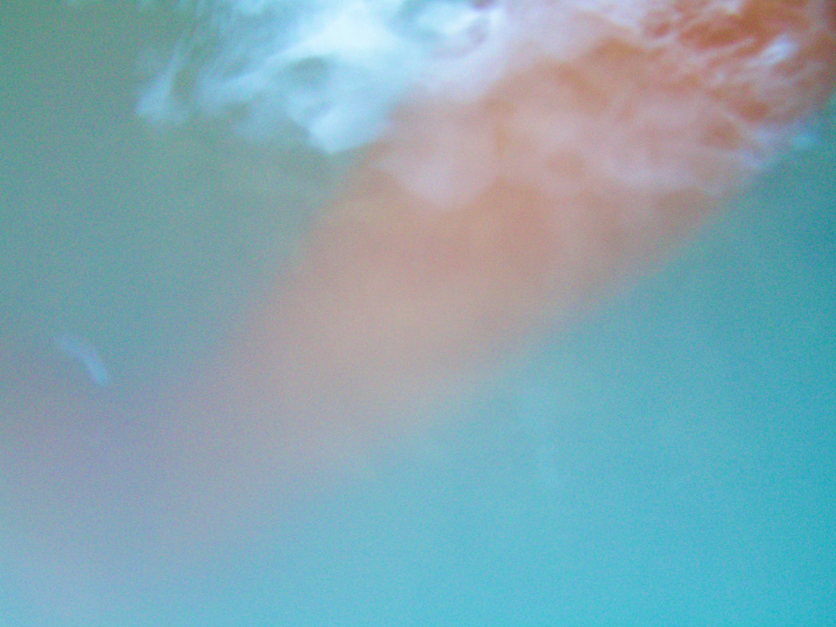 An abstract close-up of a soft peach-pink textured area blending into a turquoise blue background, with no clearly identifiable product, person, packaging, or environment.