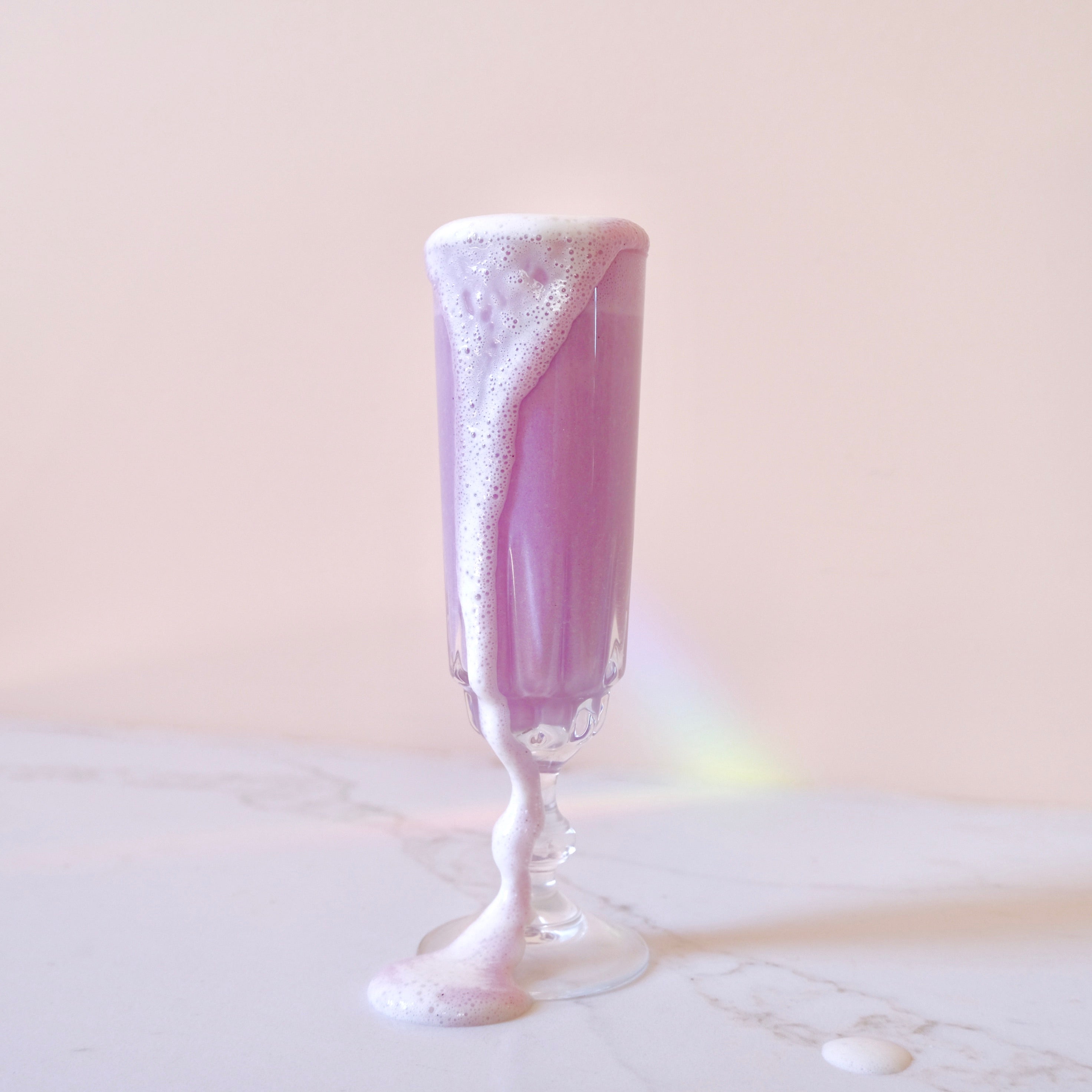 ube latte with white foam on a light marble surface